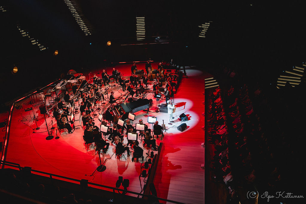 Tuure Kilpeläisen PartyTuure-sinfoniakiertueen orkesteri esiintyy valaistulla lavalla yleisön edessä