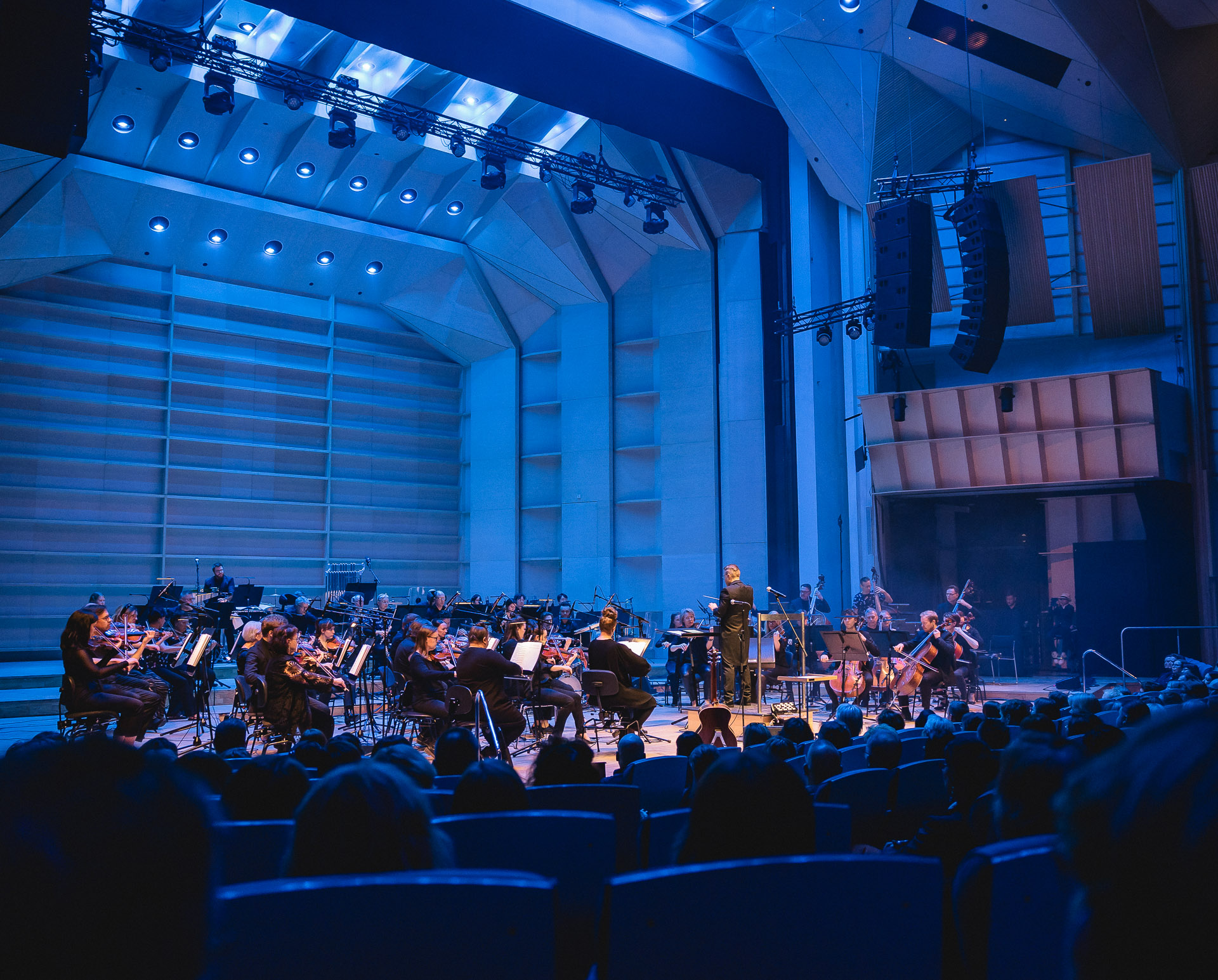 Sinfoniaorkesteri esiintyy modernissa konserttisalissa sinisessä valaistuksessa